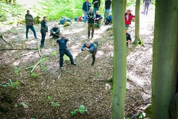 Teilnehmer überquert eine selbstgebaute Seilbrücke zwischen Bäumen