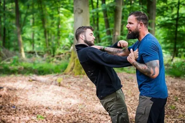 Zwei Männer üben eine Selbstverteidigungstechnik im Wald