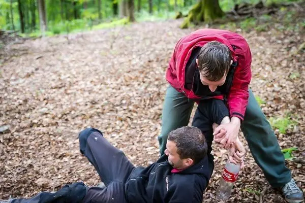 Zwei Personen im Wald, eine Person hält die andere am Arm fest
