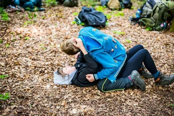 Zwei Personen liegen auf dem Boden und üben eine Kampftechnik im Laub