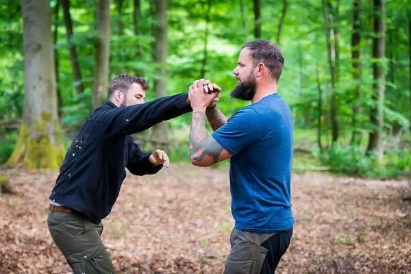 Zwei Personen üben eine Selbstverteidigungstechnik im Wald