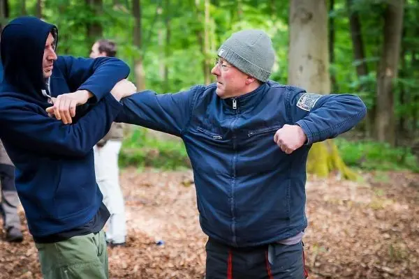 Zwei Personen üben eine Selbstverteidigungstechnik im Wald