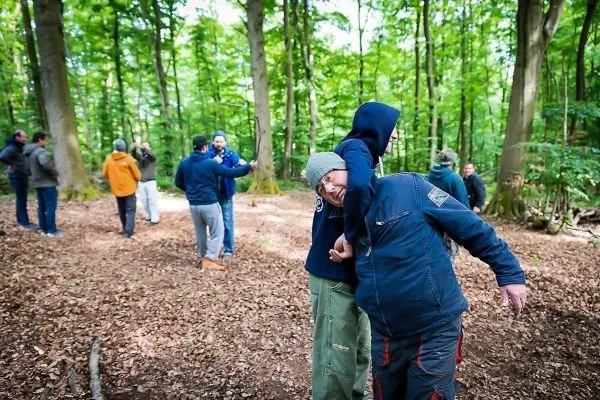 Zwei Personen üben eine Technik zur Selbstverteidigung im Wald
