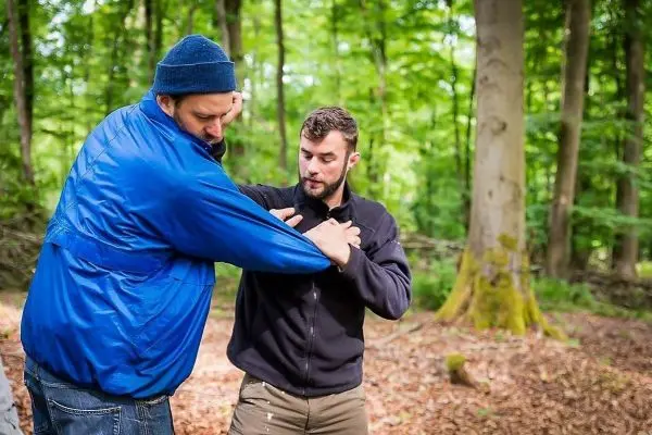 Zwei Personen üben eine Technik zur Selbstverteidigung im Wald