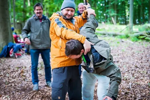 Zwei Personen üben eine Technik zur Unterstützung in einer Notsituation im Wald