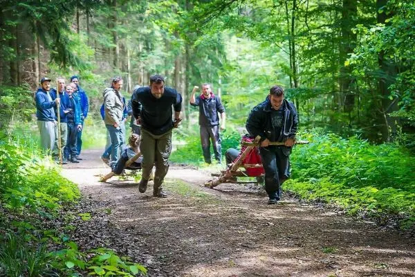 Zwei Personen ziehen eine improvisierte Trage auf einem Waldweg