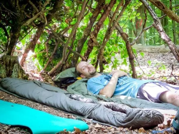 Biwak unter einem selbstgebauten Unterstand aus Ästen und Blättern