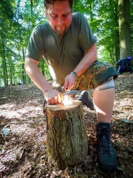 Feuerstahl erzeugt Funken auf Zunder auf einem Baumstumpf im Wald