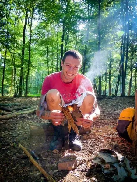 Kleine Flamme raucht aus Zunder in der Hand