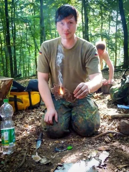 Kneeling in the forest, Zunder glimmt auf einem Blatt in der Hand