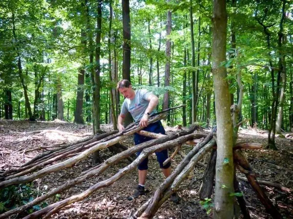 Mann baut eine improvisierte Unterkunft aus Ästen im Wald
