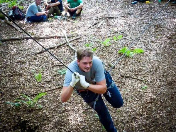 Mann überquert eine selbstgebaute Seilbrücke im Wald