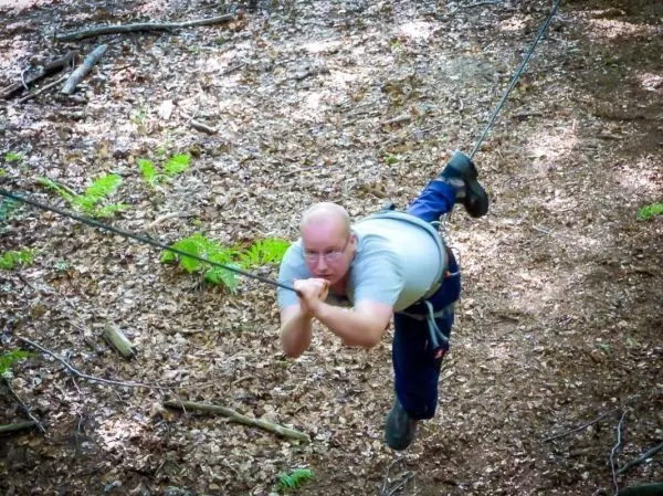 Mann überquert selbstgebaute Seilbrücke in einem Waldgebiet