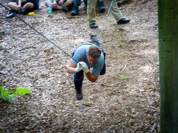 Mann überquert selbstgebaute Seilbrücke in einem Waldgebiet