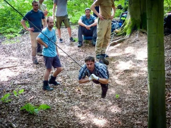 Mann überquert selbstgebaute Seilbrücke, während andere zuschauen