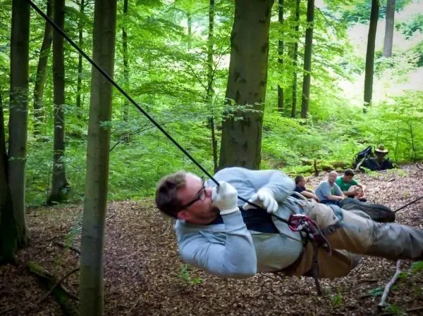 Mann überquert selbstgebaute Seilbrücke zwischen Bäumen im Wald