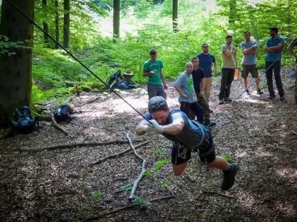 Mann überquert selbstgebaute Seilbrücke zwischen Bäumen im Wald