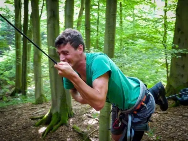 Mann zieht an einem Seil in einem Waldgebiet