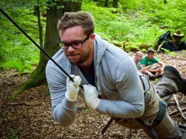 Mann zieht sich an einem Seil in einem Wald hoch