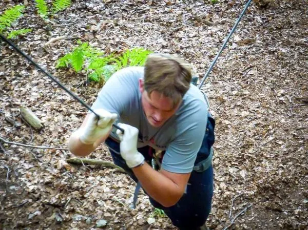 Mann zieht sich an einem Seil in einem Waldgebiet hoch