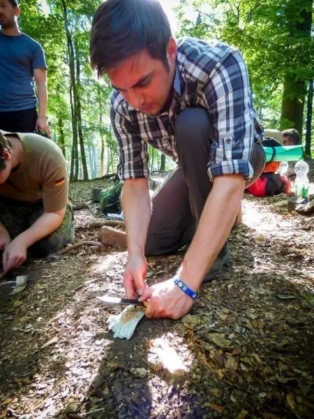 Messer schneidet Holzstück auf dem Waldboden