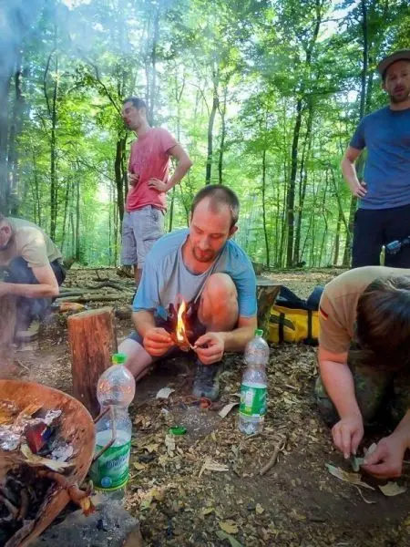 Person entzündet Feuer mit Zunder im Wald beim Survival Training
