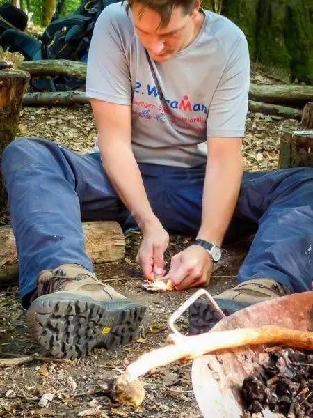 Person entzündet Feuer mit Zunder im Wald beim Survival Training