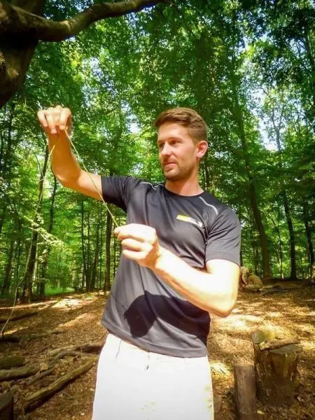 Person hält einen Faden in der Hand im Wald