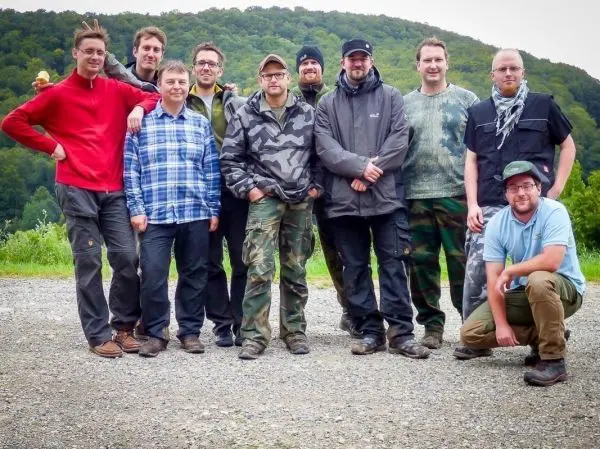 Gruppierung von zehn Personen in Outdoor-Bekleidung auf einem Schotterplatz