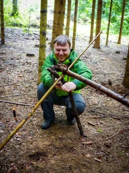 Person baut eine selbstgebaute Seilbrücke im Wald