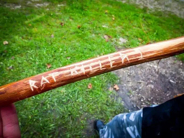 Person hält einen Stock mit eingravierter Schrift