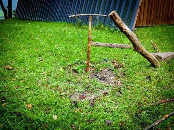 Selbstgebaute Falle aus Holz und Schnur im Gras