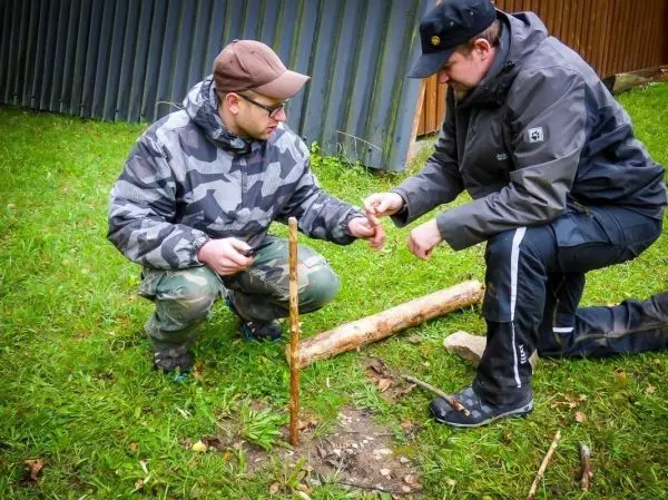 Zwei Personen arbeiten an einem Stock im Boden beim Überlebenstraining