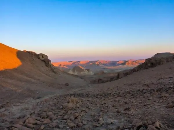 Bergige Landschaft mit steiniger Ebene und sanften Hügeln im Hintergrund