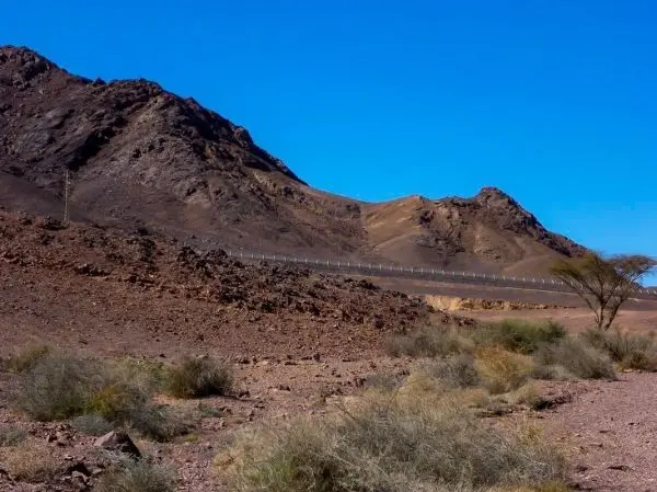 Berglandschaft mit steilen Hängen und einem Zaun im Vordergrund