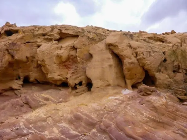 Felsformation mit glatter Oberfläche und erodierten Strukturen in sandiger Umgebung