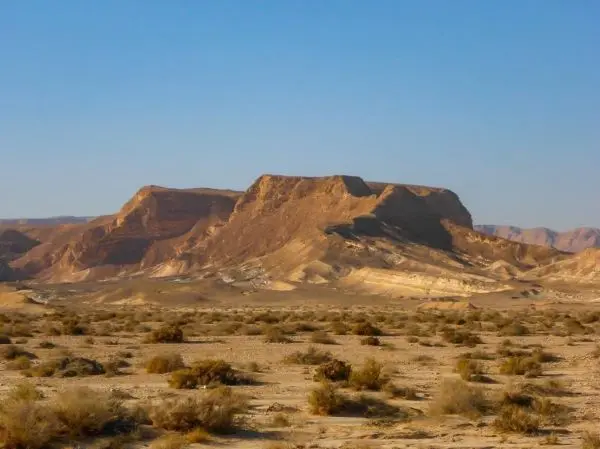 Felsformationen und Sträucher in einer trockenen Wüstenlandschaft