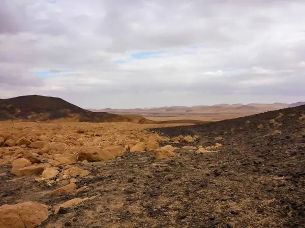 Karge, felsige Landschaft mit braunen und schwarzen Gesteinen unter bewölktem Himmel