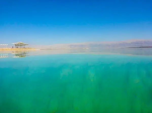 Klares Wasser mit blauer Reflexion und flachem Ufer unter klarem Himmel