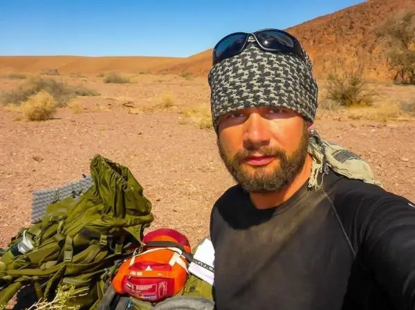 Rucksack und Ausrüstung liegen auf dem Boden in einer Wüstenlandschaft
