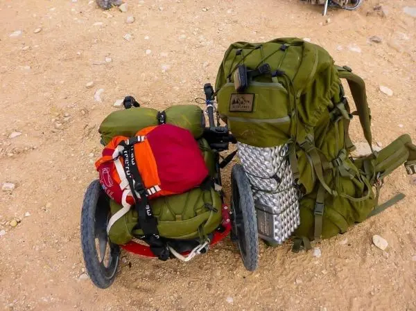Rucksack und Gepäck auf einem Wagen im sandigen Gelände