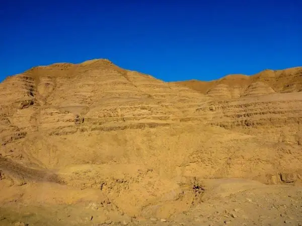 Sandige Hügel mit geschichteten Felsen unter klarem blauen Himmel