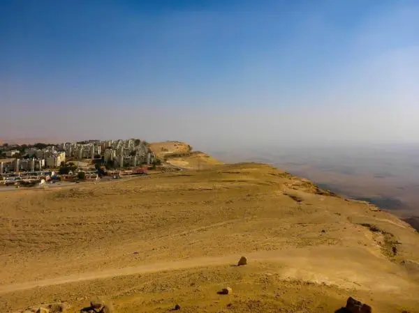 Städtische Bebauung am Rand einer kargen, sandigen Landschaft unter blauem Himmel