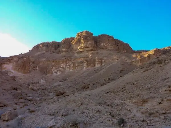 Steile Felswand mit gerölligem Untergrund und klarem Himmel im Hintergrund