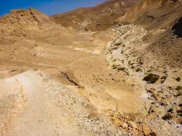 Trockene, felsige Landschaft mit einem schmalen Weg und einem kleinen Flussbett