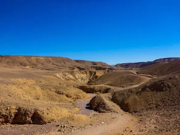 Trockene, hügelige Landschaft mit einem schmalen Weg zwischen den Erhebungen