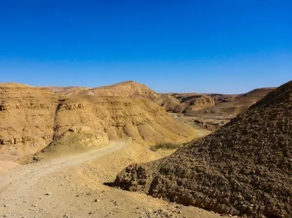 Trockene, hügelige Landschaft mit sandigem Boden und klarem Himmel