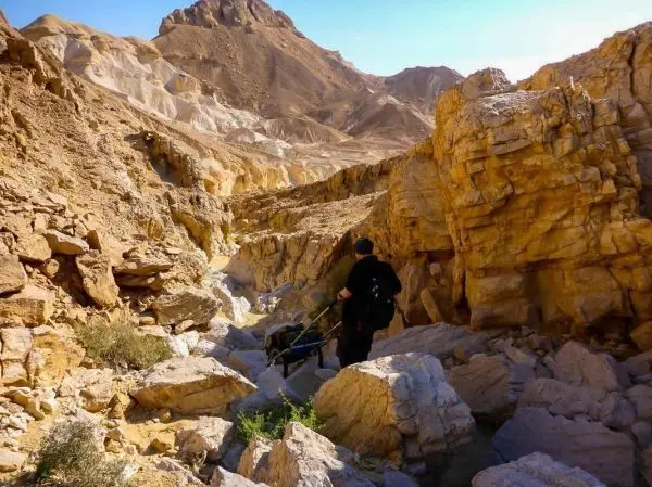 Wanderer mit Rucksack geht durch eine felsige Schlucht zwischen hohen Felsen