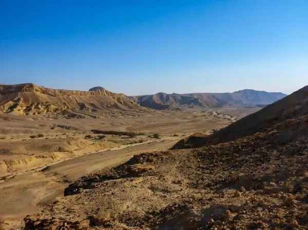 Weite, trockene Landschaft mit Hügeln und Felsen unter klarem Himmel