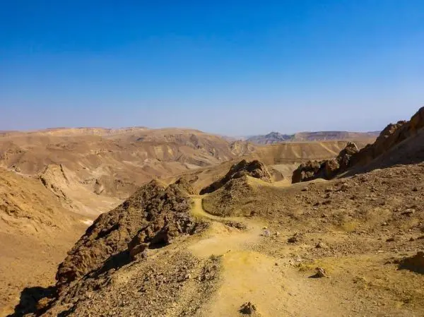 Wüstenlandschaft mit steinigen Hügeln und einem schmalen Pfad im Vordergrund